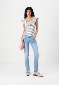 Črtasta bluzka brez naramnic z nabranimi robovi; svetlo modri jeans in svetlo roza torbica. Upoštevano z kremnimi balerinkami z zaponkami.