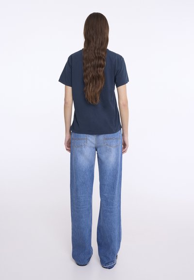 Tricou din bumbac bleumarin cu mâneci scurte, combinat cu blugi din denim albastru deschis, tip lejer. Materialul pare moale și are o croială casual.