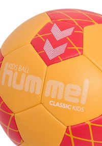 Gul og rød fodbold med hexagonale paneler, der har en tekstureret overflade og logoet "hummel CLASSIC KIDS" i fed hvid skrift.