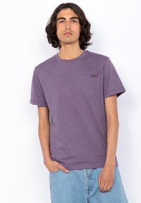 T-shirt viola a girocollo realizzato in morbido tessuto, con taschino e applicazione del logo. Maniche corte e vestibilità comoda. Design casual.