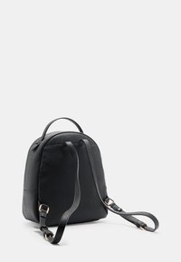 Melnas mākslīgās ādas mugursoma ar noapaļotu formu, regulējamām lencītēm, augšējo rokturi un smalkām faktūras detaļām. Aprīkota ar zelta krāsas metāla aksesuāriem.