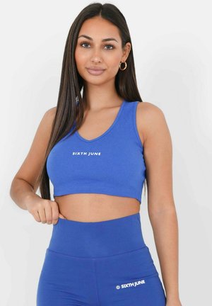 Blauwe geribbelde crop-top met brede bandjes, voorzien van een wit "SIXTH JUNE" logo; gecombineerd met bijpassende high-waisted leggings. Soepele textuur.