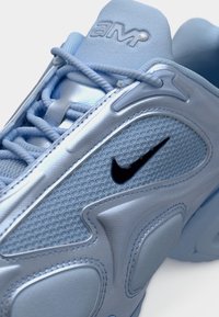 Αθλητικό sneaker ανοιχτού μπλε χρώματος από δίχτυ και συνθετικά υλικά. Διαθέτει υφασματικές λεπτομέρειες, ραφές στο ίδιο χρώμα και μαύρο λογότυπο της Nike.