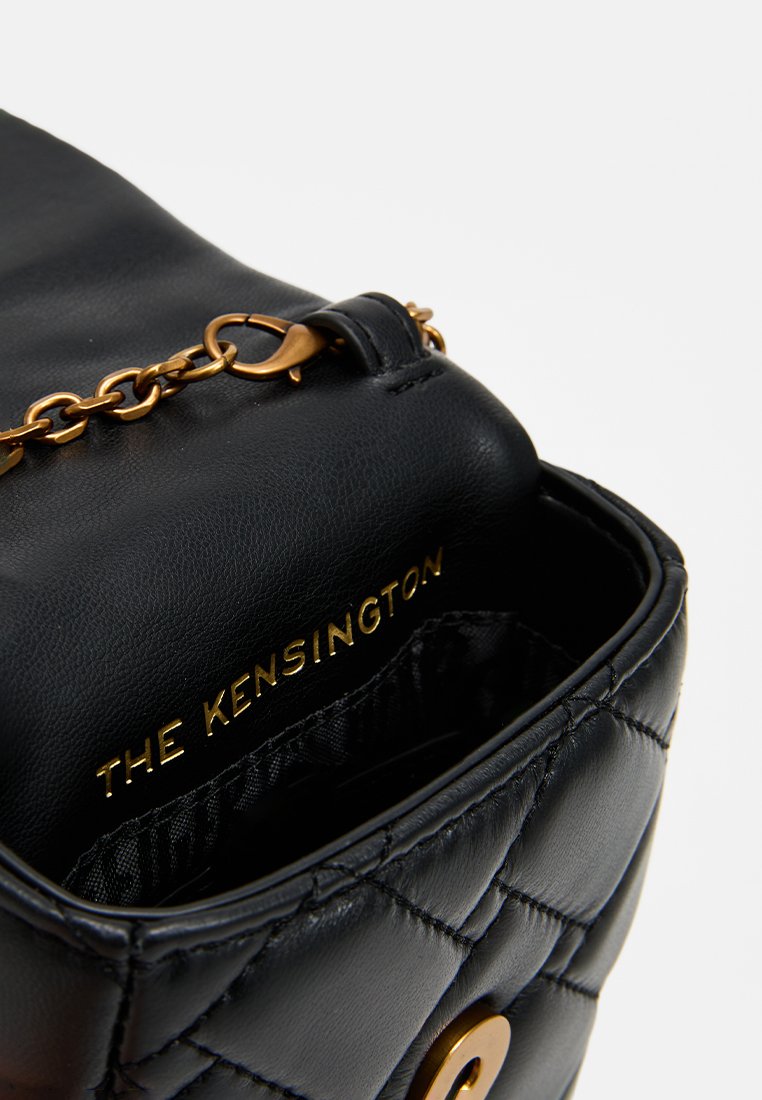 Bolso de mano de cuero negro con diseño acolchado, herrajes dorados y una correa de cadena. El interior presenta una etiqueta de marca "THE KENSINGTON."