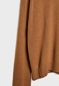 Brązowy dzianinowy sweter wykonany z miękkiego materiału, o luźnym kroju. Posiada ściągacze na rękawach i u dołu, eksponując gładką strukturę.
