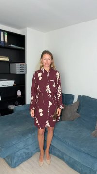 Bordo spalvos suknelė-marškiniai su gėlių raštu, su sagomis priekyje ir diržu; derinama su smėlio spalvos, smailiais bato priekiais kulnais. Pagaminta iš lygios tekstūros audinio.