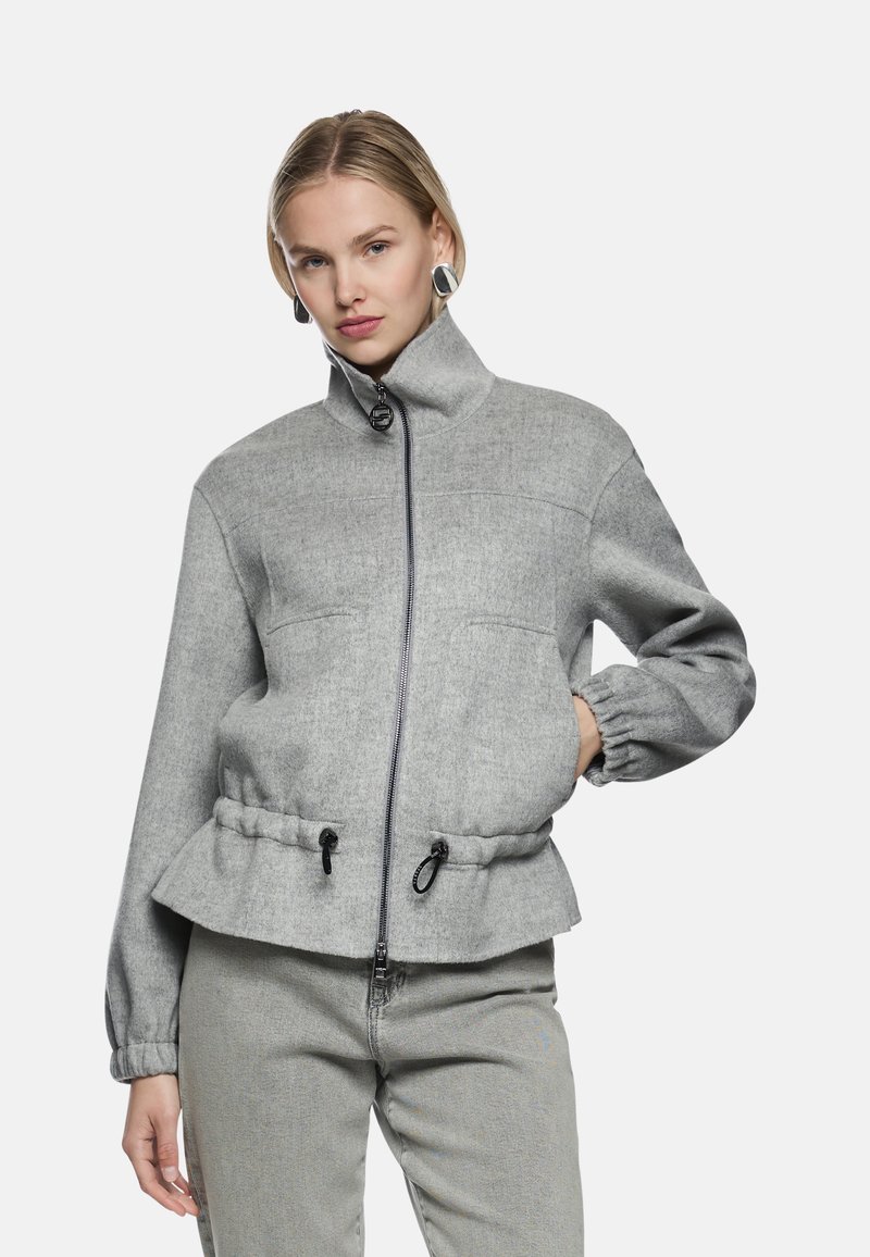 Graue Zip-up-Jacke mit hohem Kragen, elastischen Bündchen und Kordelzug an der Taille. Hergestellt aus strukturiertem Stoff, mit zwei Vordertaschen.