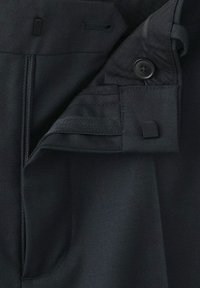 Pantalon noir en tissu lisse, avec fermeture éclair, bouton et poches latérales. Comprend une texture subtile et des coutures nettes.