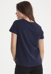 Mørkeblå t-shirt med korte ærmer, rund halsudskæring og en afslappet pasform. Glat bomuldsstof med minimale syninger.