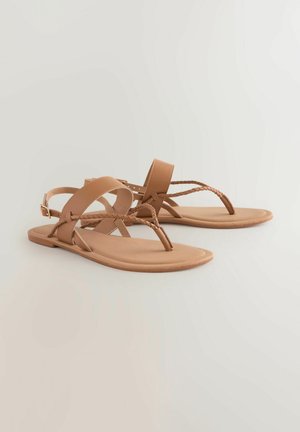 Sandalias planas marrones hechas de material sintético. Presentan correas entrelazadas y un posteo para los dedos. Textura suave con un diseño minimalista.