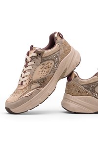 Chaussures de sport beige et marron avec semelles épaisses, décorées de petits clous dorés et argentés et lacets blancs, vues de côté et de dos.