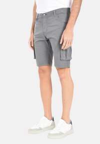 Pantaloni cargo grigi realizzati in cotone leggero. Presentano tasche laterali e una vestibilità comoda, abbinati a sneakers bianche per un contrasto.