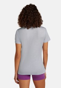 Lys grå, kortærmet t-shirt med afslappet pasform, glat tekstur og subtil glans, parret med lilla shorts. Ingen synlige logoer.