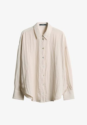 Light beige button-up shirt made of textured fabric, featuring a classic collar, long sleeves, and rounded hem. Six pearlescent buttons visible.
