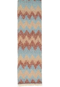 Tappeto con motivo zigzag multicolore in tonalità di blu, beige e marrone. Texture morbida con bordi sfrangiati. Forma rettangolare.