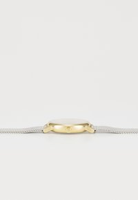 Relógio dourado com mostrador redondo, pulseira de malha prateada, dois botões laterais e um design suave e minimalista.