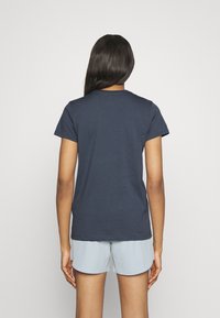 Mörkblå bomulls t-shirt med korta ärmar, rund halsringning och en slät yta, visad bakifrån. Bärs med ljusblå shorts.