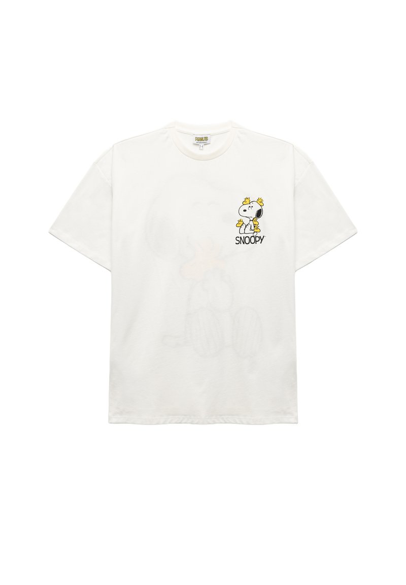 T-shirt en coton blanc présentant un dessin de Snoopy en bande dessinée avec des accents jaunes. Coupe décontractée avec des manches courtes et un col rond. Détail graphique distinctif.