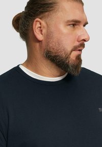 Dunkelblaues T-Shirt aus weichem Stoff, mit rundem Ausschnitt und einem weißen Innenkragen sowie einem dezenten Logo auf der Brust.