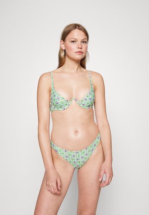 Bikini floral verde com alças ajustáveis; dispõe de um top triangular e uma parte de baixo de cintura baixa. O tecido tem uma textura suave e lisa com um padrão xadrez.