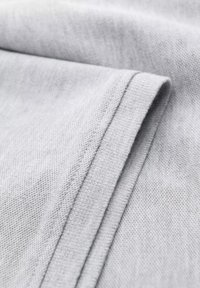 Tejido gris con una superficie suave y ligeramente texturizada, que presenta un borde doblado y una costura limpia a lo largo del dobladillo.