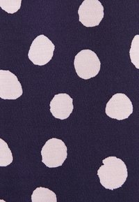 Tissu bleu marine avec de grands pois blancs de forme irrégulière dispersés de manière uniforme sur toute la surface.