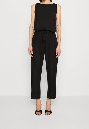 Mono negro sin mangas con escote redondo, cintura ceñida y pantalones de pierna ancha. Hecho de una tela suave y fluida.