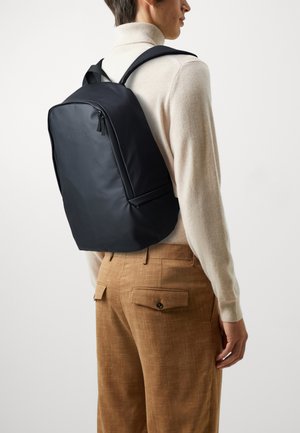 Black nylon backpack with a sleek design, featuring a front zipper pocket and padded shoulder straps. Smooth texture, minimalist style.