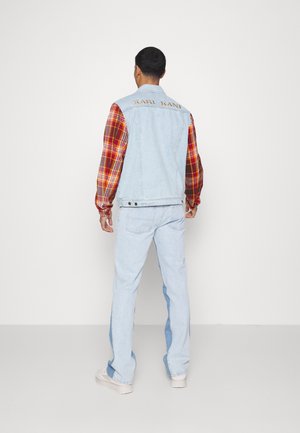Gilet di jeans azzurro chiaro con maniche lunghe a quadri rossi. Presenta un logo sul retro e jeans dritti azzurri chiari con accenti laterali.