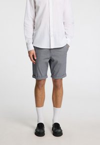 Pelēki auduma šorti ar sarullētām malām, savienoti ar baltu pogām uz augšu kreklu, baltām zeķēm un melniem loafers. Vienkāršs dizains un neitrālas krāsas.
