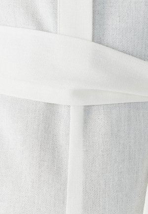 White canvas bag with textured fabric, featuring a wide white strap wrapping around the body, creating a distinct layered appearance.