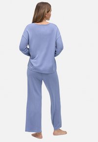 Conjunto de loungewear azul claro que incluye una camiseta de manga larga holgada y pantalones de pierna ancha, confeccionados con una tela suave, con un diseño simple y costuras mínimas.