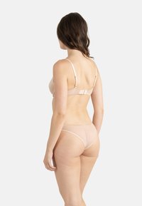 Ensemble de lingerie couleur chair comprenant un soutien-gorge lisse avec des bretelles réglables et un string sans couture. Tissu doux et extensible avec un minimum de détails.