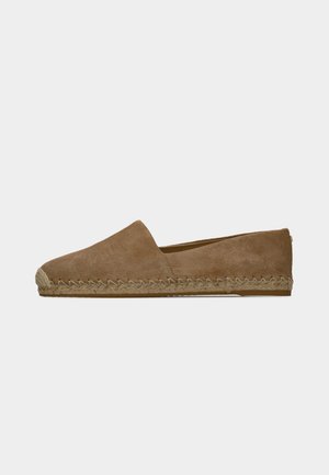 Brauner Wildleder-Espadrille-Slipper mit geflochtenen Details entlang der Sohle, flachem Absatz und abgerundeter Spitze vor weißem Hintergrund.