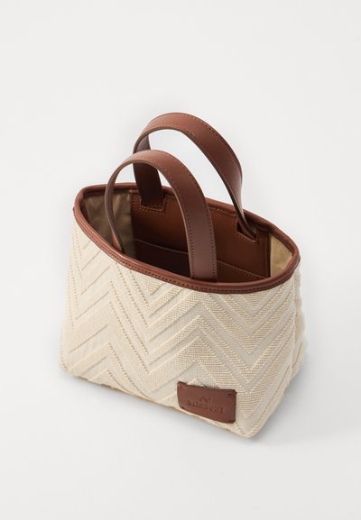 Sac en tissu crème avec une texture en chevron, anses en cuir marron et un petit patch logo. Ouvert sur le dessus, intérieur doublé de matière beige.