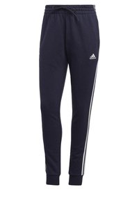 Mörkblåa joggingbyxor i mjukt tyg, med elastisk midjeresår och dragsko, vita sidoremsor och en diskret logotypdetalj.