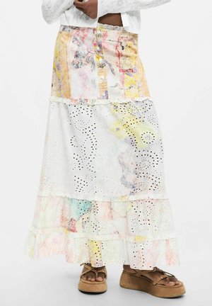 Patchwork seelik silmusega pitspaneelidega pastelltoonides, pruuni platvormsandaalidega modelli seljas valgel taustal.