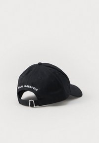 Gorra de béisbol negra con visera curva y correa ajustable. Presenta bordado blanco "KARL LAGERFELD" en la parte posterior. Material de algodón.