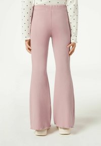 Pantalones flared de canalé en rosa claro con una cinturilla elástica, que presentan una superficie texturizada y un dobladillo que se abre ligeramente en la parte inferior.