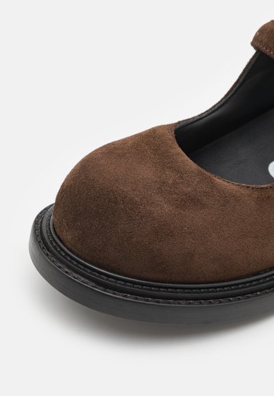 Pantof brown din suede, cu vârful rotund, căptușeală interioară neagră și o talpă exterioară groasă neagră, cu detalii de cusătură.