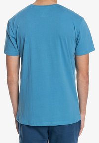 Short-sleeved, round-neck T-shirt in solid blue cotton, with a smooth texture and no visible patterns. Cleanly finished edges.
