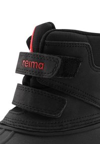 Svart ankelstövel med en slät textur, justerbar kardborreband med röda accenter och förstärkt tå. Varumärket "relima" synligt.