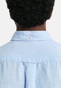 Lichtblauwe, kortekolen overhemd met een button-down kraag. Gemaakt van een gestructureerde stof met een achteryoke en een klein knoopdetail bij de kraag.