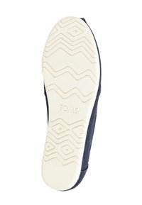 Σόλα παπουτσιού TOMS σε ναυτικό μπλε χρώμα χωρίς κορδόνια με λευκή λαστιχένια εξωτερική σόλα που διαθέτει διαμάντι και ζιγκ-ζαγκ μοτίβα πέλματος και το λογότυπο TOMS.