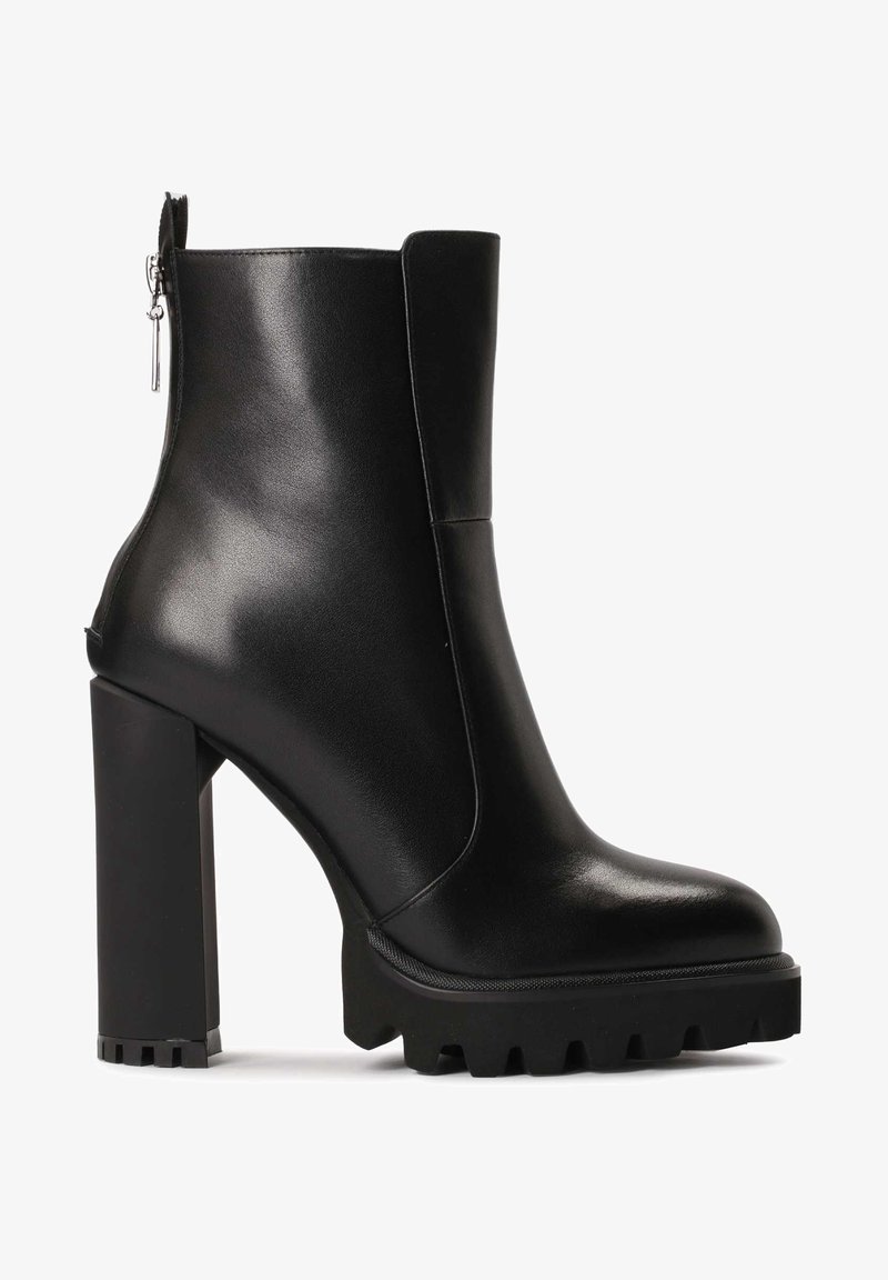 Stivale alla caviglia in pelle nera con tacco largo alto. Presenta una chiusura con zip sul retro e una suola testurizzata con scanalature profonde per una buona aderenza.