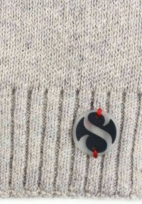 Light gray knitted beanie with a ribbed texture. Features a circular black logo tag with red thread attachment.