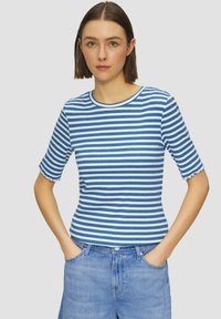 Camiseta de manga corta a rayas azul y blanca con escote redondo y puños con ondas. El material parece suave y ajustado. Los detalles incluyen un bolsillo en la parte delantera.