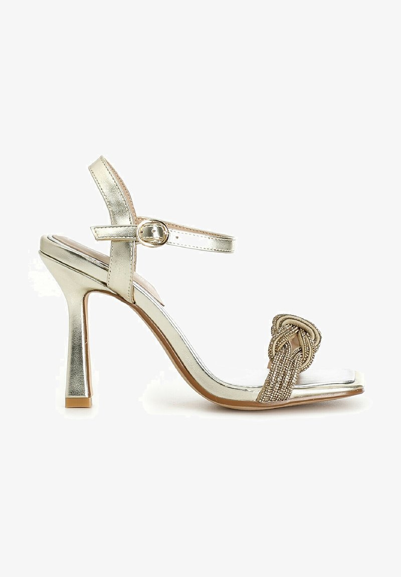 Metallic silberne High-Heels-Sandalen verfügen über einen schmalen Knöchelriemen mit einer Schnalle, einen geflochtenen Vorderfußriemen mit Perlen und eine durchsichtige Fußbett.