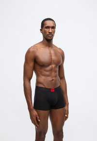 Μαύρα boxer briefs με κόκκινη μέση με λογότυπο, κατασκευασμένα από λείο, ελαστικό ύφασμα, με εφαρμοστή σχεδίαση και μήκος έως το μέσο του μηρού.