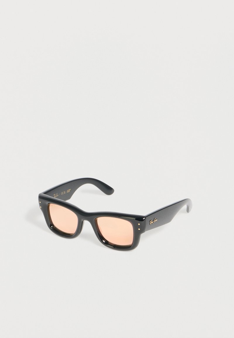 Μαύρα ορθογώνια γυαλιά ηλίου Ray-Ban με ανοιχτό ροζ φακούς που ακουμπούν σε λευκή επιφάνεια.